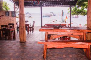 a restaurant with tables and chairs and the water at COCONUT BEACH BUNGALOWS & WARUNG Exst Teman-Teman 2 garden view in Amed