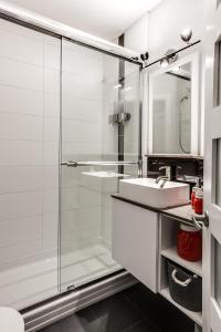 La salle de bains est pourvue d'une douche en verre et d'un lavabo. dans l'établissement Le Villageois by Gestion ELITE, à Mont-Tremblant