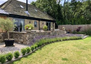 a garden with a stone retaining wall and a house at Harrogate Barns in Harrogate