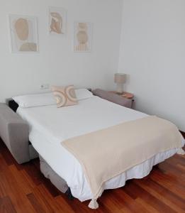 Cama blanca en habitación con suelo de madera en Pura Playa - Rías Baixas - Galicia, en Cangas de Morrazo