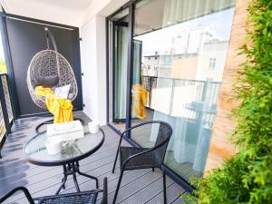 a balcony with a table and chairs and a swing at MK Apartamenty Młyńska 10 in Kołobrzeg