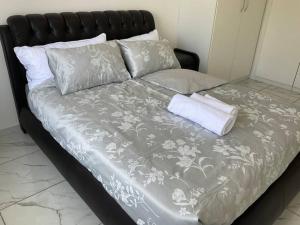 ein Bett mit einer grauen und weißen Decke und Kissen in der Unterkunft Lovely 1 Bedroom Unit in an Amazing Golf Estate in Roodepoort
