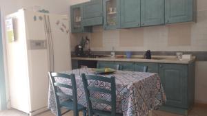 y cocina con mesa, sillas y nevera. en Casa Flavia en Porto Pino