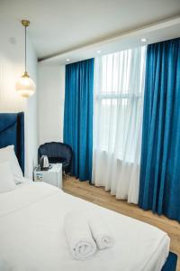 Schlafzimmer mit einem Bett mit blauen und weißen Vorhängen in der Unterkunft Sky apartmani & spa in Leskovac