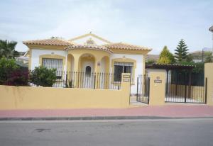 una casa amarilla con una valla delante de ella en Villa Nala, en Mazarrón
