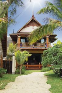 dom z balkonem i palmami przed nim w obiekcie Sankhara Private Beach Luxury Villas w mieście Poste Lafayette