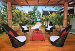 une terrasse en bois avec une table et des chaises. dans l'établissement Sankhara Private Beach Luxury Villas, à Poste Lafayette
