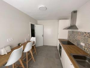 eine Küche mit weißen Wänden und einer Theke mit weißen Stühlen in der Unterkunft Arena Playa Gijón by Flowhome in Gijón