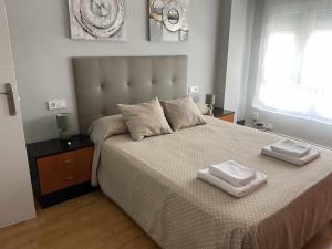 a bedroom with a large bed with two towels on it at Arena Playa Gijón by Flowhome in Gijón