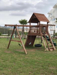 un parque infantil de madera con un tobogán y un columpio en Smir park Appartment, en Marina Smir
