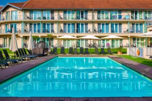 una piscina frente a un hotel con sillas y sombrillas en Holiday Resorts, en Balatonszárszó