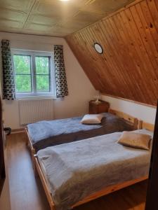 2 bedden in een kamer met houten plafonds bij Stuga Horni Blatna in Horní Blatná