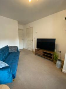 a living room with a blue couch and a flat screen tv at Kingfisher House in Mexborough