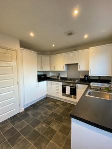 a large kitchen with white cabinets and a sink at Kingfisher House in Mexborough