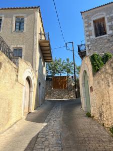 an alley between two stone buildings with trees in the distance at Xenonas Nikia in Yerákion