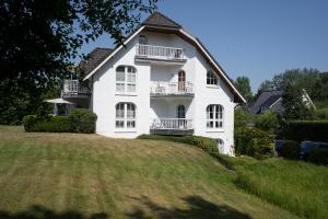 Biały dom na szczycie trawiastego wzgórza w obiekcie Haus Pegasus App 7 w mieście Scharbeutz