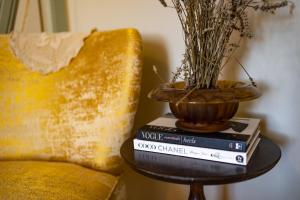 una mesa con libros y un jarrón encima de un sofá en Luxueuses Suites & Chambres d'hôtes - accueil champagne, petit-déjeuner - Maison Champagne, en Condom