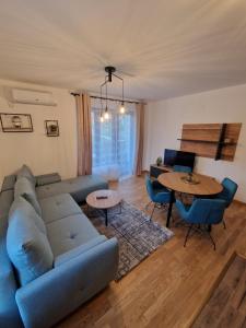 un soggiorno con divano blu e tavolo di Nina Apartman 2 a Soko Banja