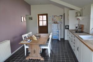 een keuken met een houten tafel en witte stoelen bij Gîte l' Ancien Four - De Bakoven in Lessines