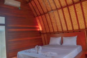 ein Schlafzimmer mit zwei weißen Handtüchern auf einem Bett in der Unterkunft Laba Laba Bungalow in Gili Meno