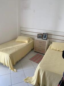 um quarto com 2 camas e uma cómoda e uma janela em Apartamento em Caraguatatuba em Frente a Praia em Caraguatatuba