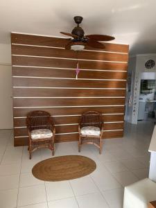 Duas cadeiras de vime e uma ventoinha de tecto num quarto em Apartamento em Caraguatatuba em Frente a Praia em Caraguatatuba