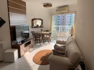 - un salon avec un canapé, une télévision et une table dans l'établissement Apartamento em Caraguatatuba em Frente a Praia, à Caraguatatuba