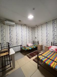 a room with two beds and a table and chairs at Bereke Hostel in Shymkent