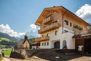 un gran edificio con balcón y iglesia en Lippmöshof Apartment Reguz, en Villnoss