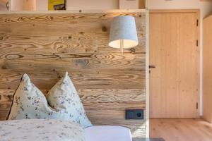 een slaapkamer met een houten muur en een bed met kussens bij Apartment Reguz in Villnoss