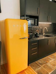 un réfrigérateur jaune dans une cuisine avec des armoires noires dans l'établissement Preia-Mar Duplex Setúbal Miradouro, à Setúbal
