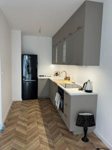 a kitchen with a black refrigerator and wooden floors at Uroczy apartament z ogrodem in Rumia