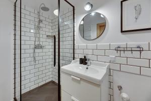 ein weißes Badezimmer mit einem Waschbecken und einem Spiegel in der Unterkunft Bastion Wałowa Comfort Apartments in Danzig