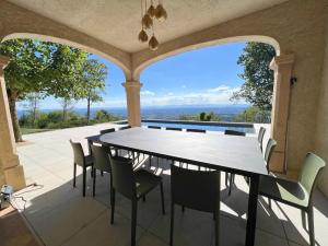 - une table et des chaises sur une terrasse avec vue dans l'établissement Bienvenue au Mas du Roulier, villa provençale avec vue hypnotique sur la chaine des Puys, à Thiers