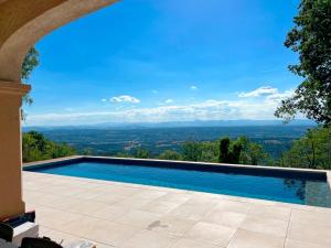 uma piscina com vista de uma casa em Bienvenue au Mas du Roulier, villa provençale avec vue hypnotique sur la chaine des Puys em Thiers