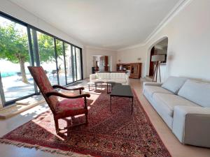 uma sala de estar com um sofá e uma cadeira em Bienvenue au Mas du Roulier, villa provençale avec vue hypnotique sur la chaine des Puys em Thiers