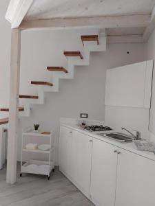 une cuisine blanche avec un escalier dans le mur dans l'établissement Fradalisa Delizioso monolocale a Vico Equense, à Vico Equense