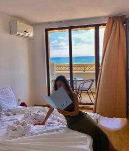 a woman laying on a bed reading a book at Teos Apartments Primorsko in Primorsko +80 photos