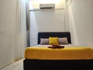 - une chambre avec un lit et une couverture jaune dans l'établissement ezzahrahsyariahhomestay, à Sandakan