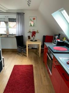 cocina con mesa y alfombra roja en FeWo "Zwischen den Meeren" en Rendsburg