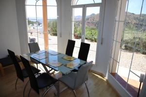 a dining room with a glass table and chairs at Villa Meretseger in Almogía