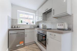 a kitchen with white cabinets and a sink and a microwave at Tanna Estates - George Street House in Leamington Spa