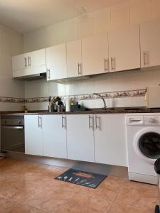 a kitchen with white cabinets and a washing machine at Casa España Sol in Vigo