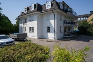 a white house with a car parked in front of it at Haus am Kurpark Timmendorfer Strand Wohnung 4 in Timmendorfer Strand