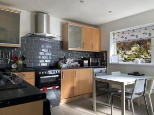 a kitchen with a table and a white table in it at No 8 Snowdonia. 3 Bedroom, sleeps 5. Pets accepted in Blaenau-Ffestiniog