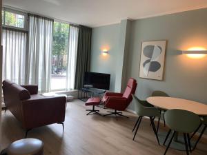 ein Wohnzimmer mit Stühlen, einem Tisch und einem TV in der Unterkunft Stadshotel aan de IJssel in hartje Deventer in Deventer