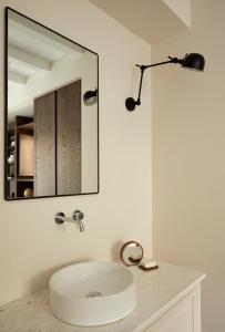 bagno con lavandino bianco e specchio di The Storyteller Boutique House a Kalabaka