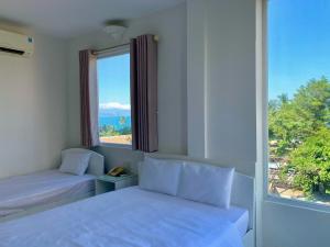 a bedroom with two beds and a large window at Oasis Nha Trang Hotel in Nha Trang