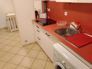 - une cuisine avec un évier et un mur rouge dans l'établissement Terrace Flat Near The City Centre, à Brives-Charensac