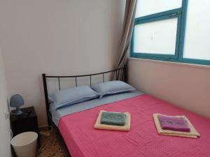 een slaapkamer met een roze bed en 2 handdoeken bij PURE URBAN ACROPOLIS METRO PETRALONA in Athene